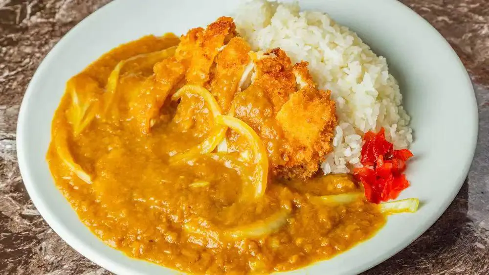 Curry Rice with Pork Cutlet consists of white rice served alongside a breaded and fried pork cutlet, covered in a thick, flavorful curry sauce at Kokoro Sushi, a Japanese restaurant in CA